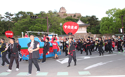 丸亀城をバックに「いまぞう丸」の山車に続いて賑やかに踊る社員や家族、協力会社の皆さん