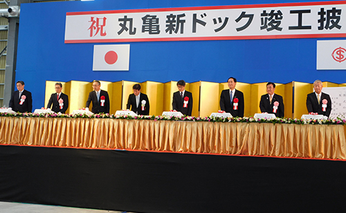 丸亀新ドック披露式で注水ボタンを押す檜垣社長（左から４人目）や浜田香川県知事（右から3人目）ら
 